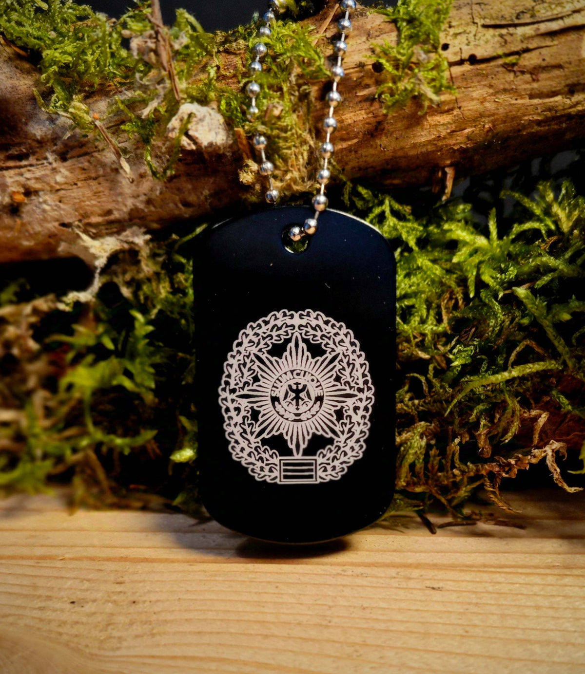Anhänger Dog Tag in schwarzer Aluminiumlegierung mit weißer Gravur eines Wappenemblems, an Kugelkette hängend