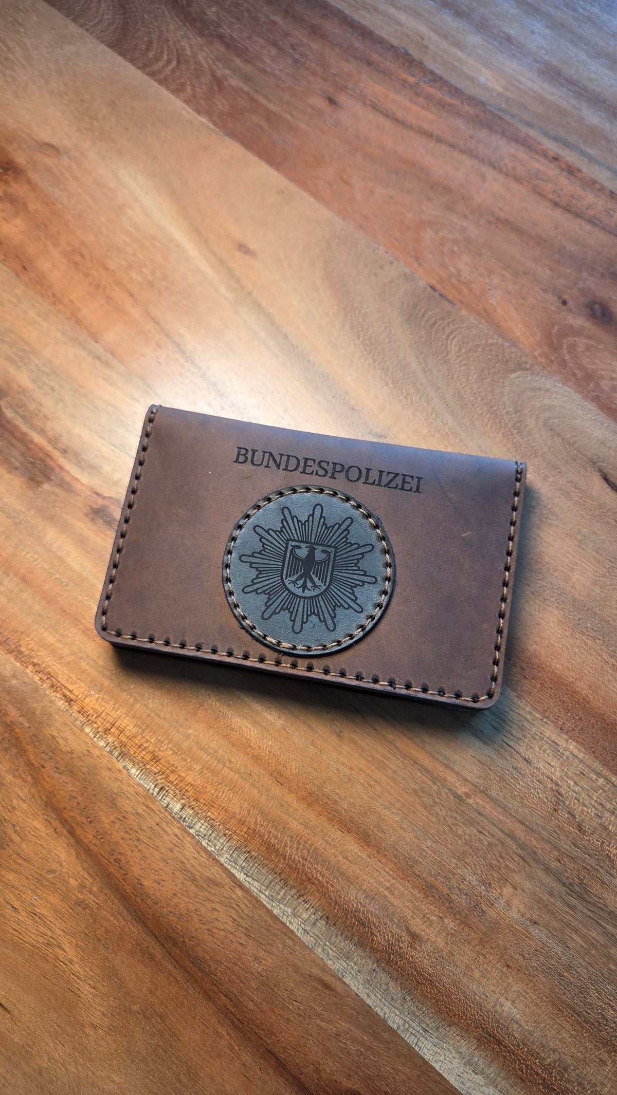 Dienstausweisetui aus Vollnarbenleder in braun mit schwarz geprägtem Bundespolizei-Emblem und Handvernähung