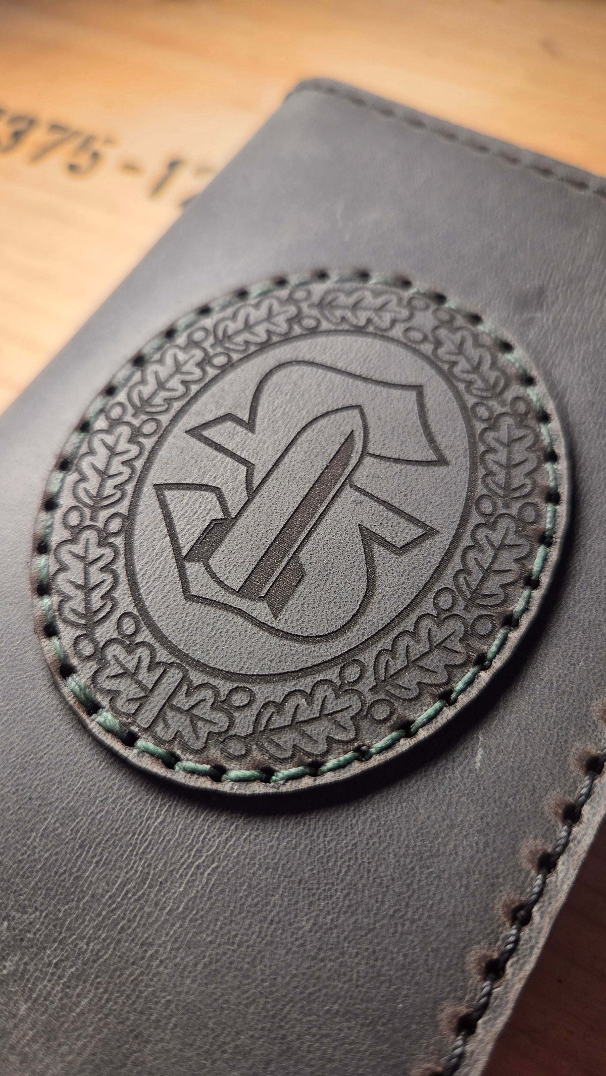 Dienstausweisetui aus Vollnarbenleder in grauschwarz mit handgenähtem Rand und geprägtem militärischem Wappen als Münzhalter