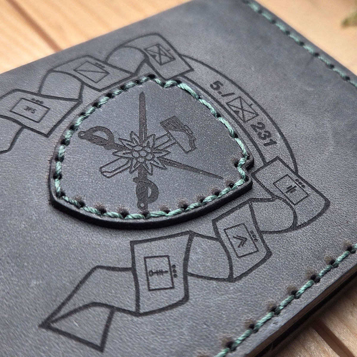 Dienstausweisetui aus Vollnarbenleder in grauschwarz mit handvernähter grüner Naht und graviertem militärischem Wappen