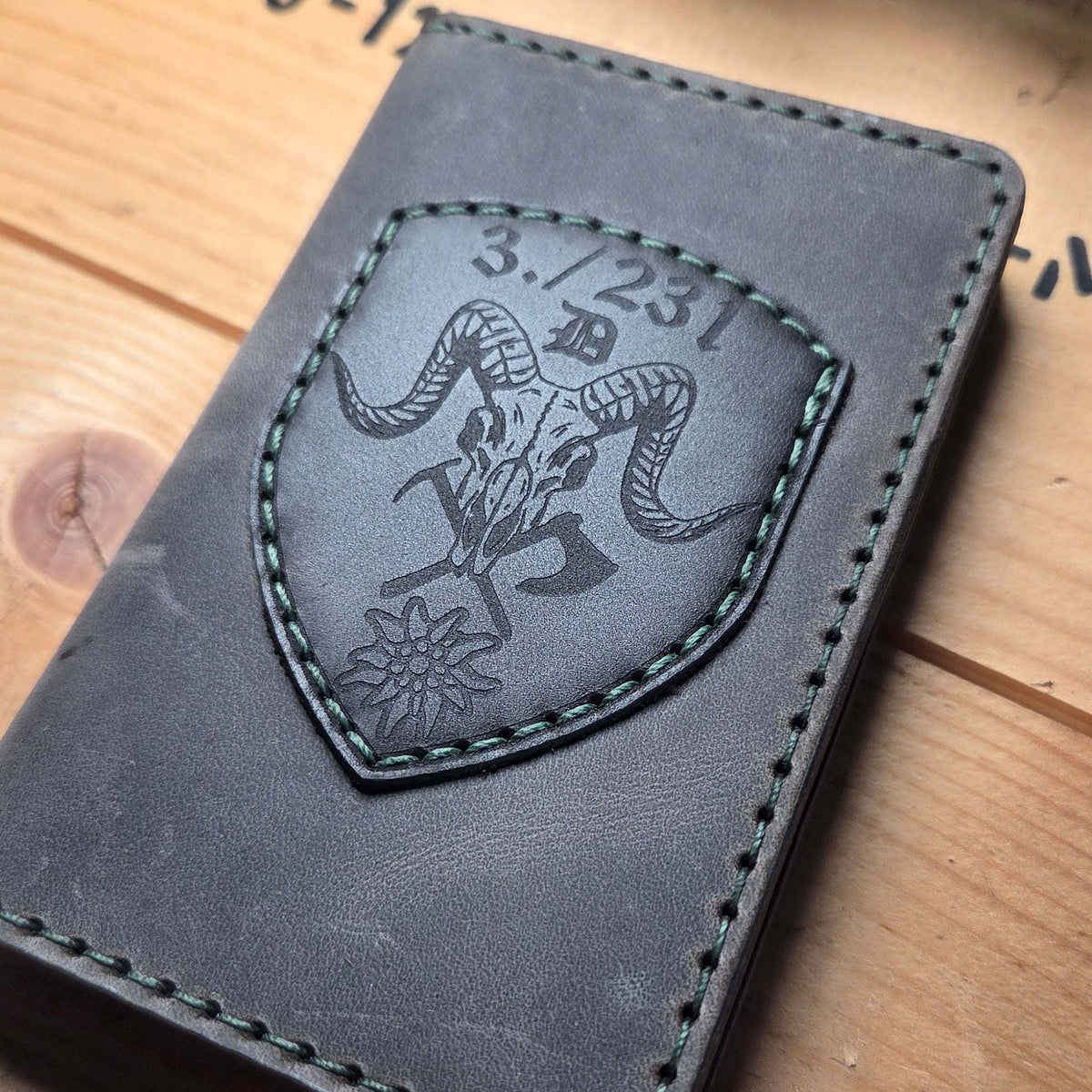 Dienstausweisetui aus Vollnarbenleder in grauschwarz mit handvernähter grüner Naht und graviertem Wappen mit Widmung