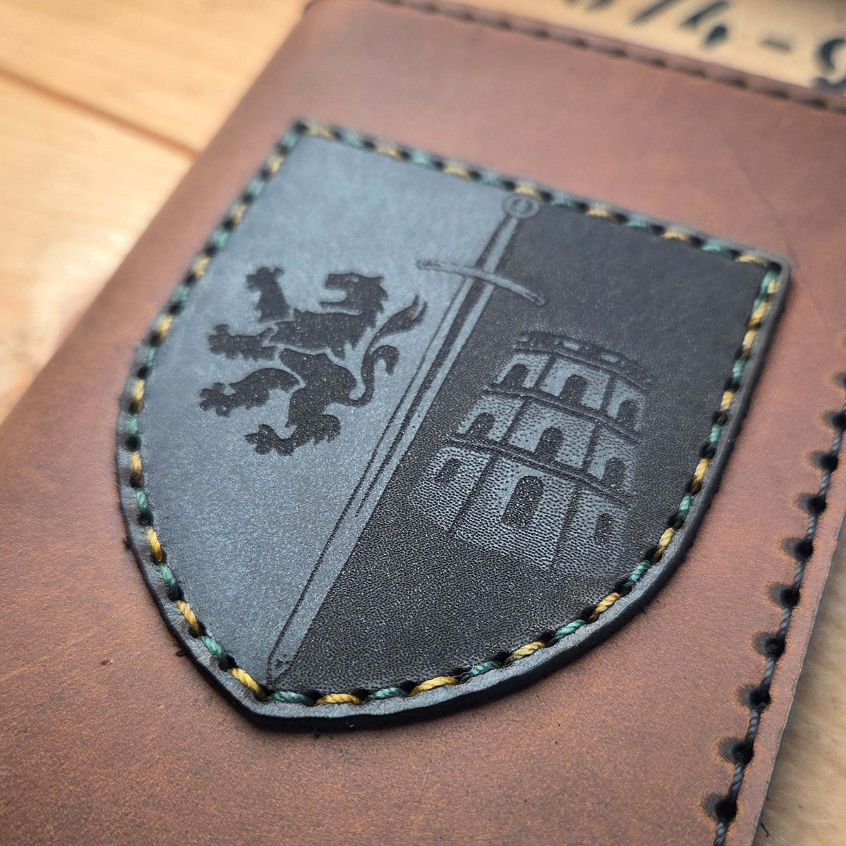 Dienstausweisetui aus Vollnarbenleder in braun mit schwarz-grauem Wappen, bestickt mit mehrfarbigen Nähten, handvernäht und graviert