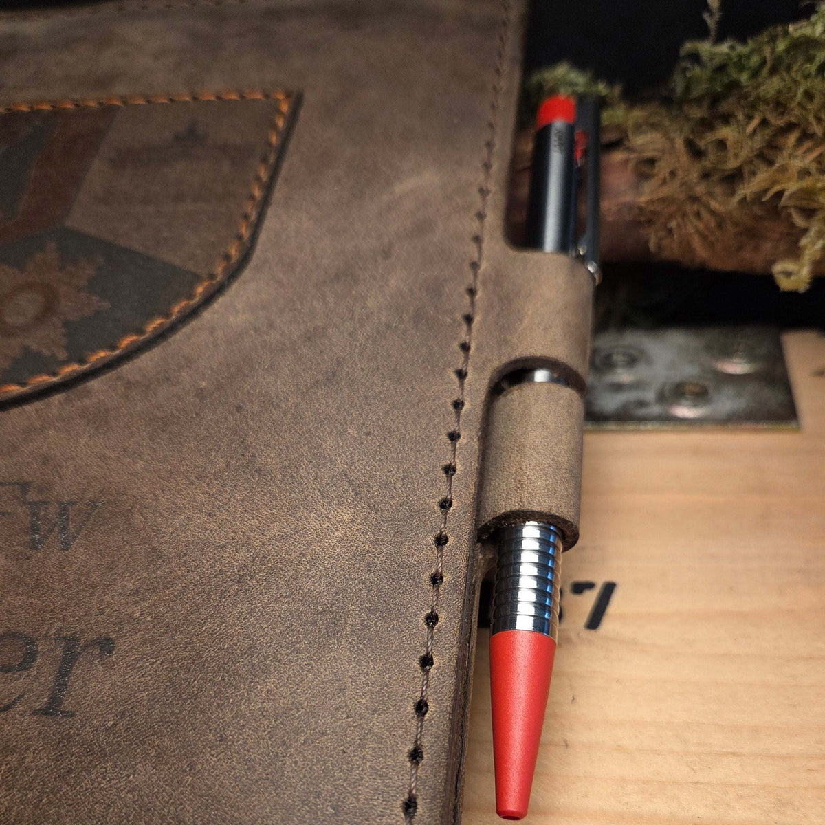DIN A5 Organizer aus braunem Leder mit handgenähter Naht, aufgenähtem Wappen und Stiftehalter mit rotem Kugelschreiber