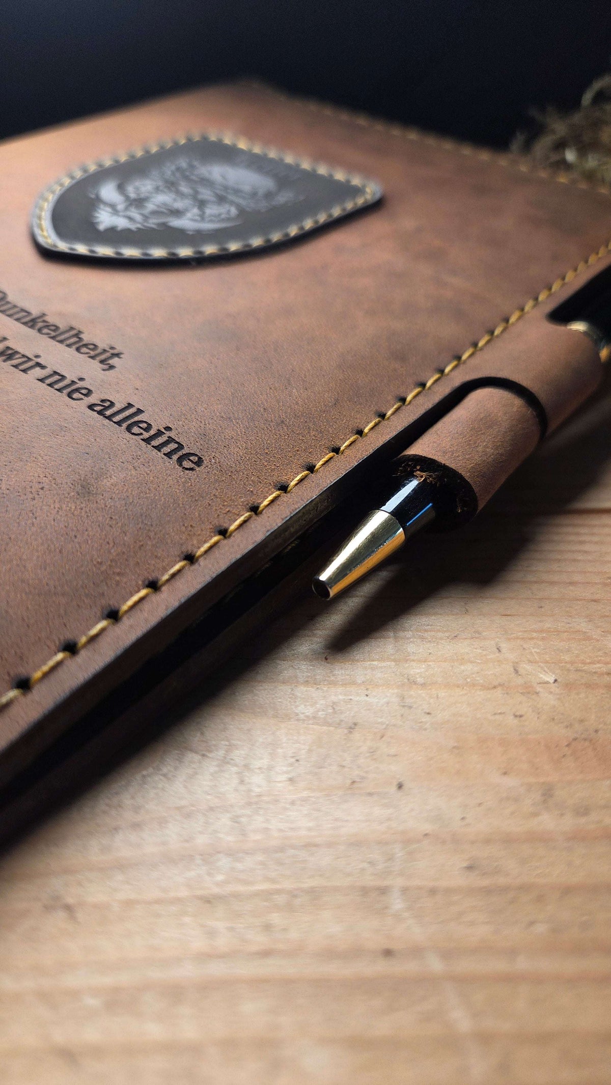 DIN A5 Organizer aus braunem Leder mit aufgenähtem Wappen und gelben Ziernähten, mit integriertem Stiftehalter und eleganter Gravur