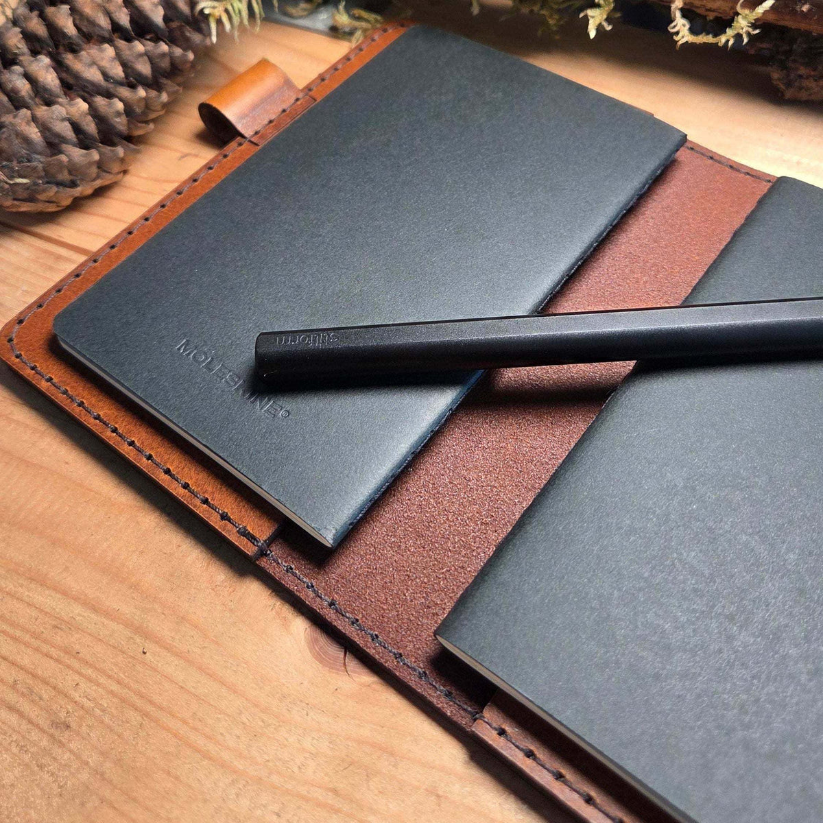 DIN A5 Organizer aus schwarzem Leder mit braunem Innenfutter, aufgesetztem Stift und Dokumentenfächern