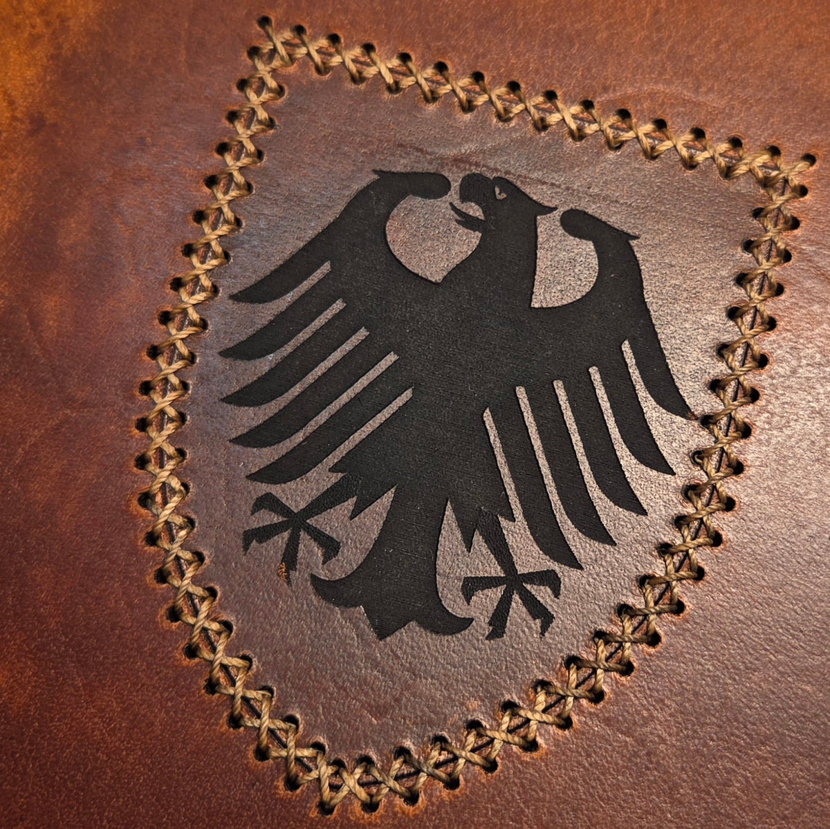 Handgefertigter DELUXE DIN A6 Organizer aus braunem Leder mit schwarzem Adlerwappen, dekorativ umnäht im Schildmuster