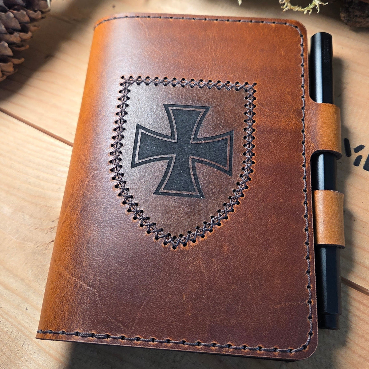 Handgefertigter DELUXE DIN A6 Organizer aus braunem Leder mit aufgenähtem schwarzen Wappen und integriertem Stiftehalter
