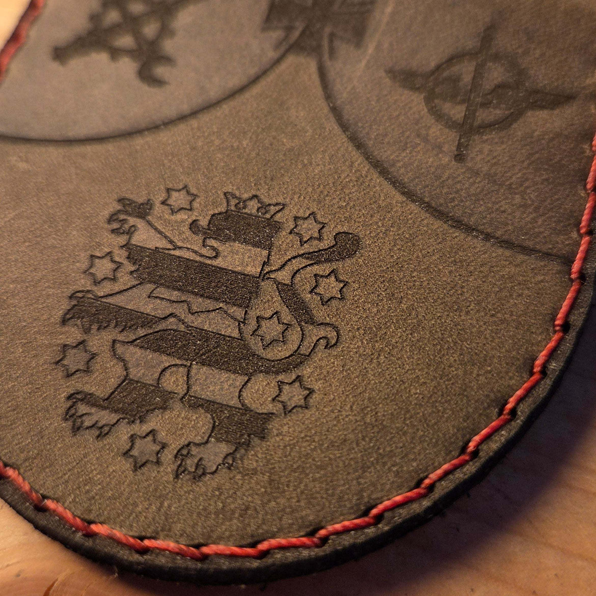 Individueller Leder Patch aus braunem Büffelleder mit handvernähter roter Naht und graviertem Wappenmotiv