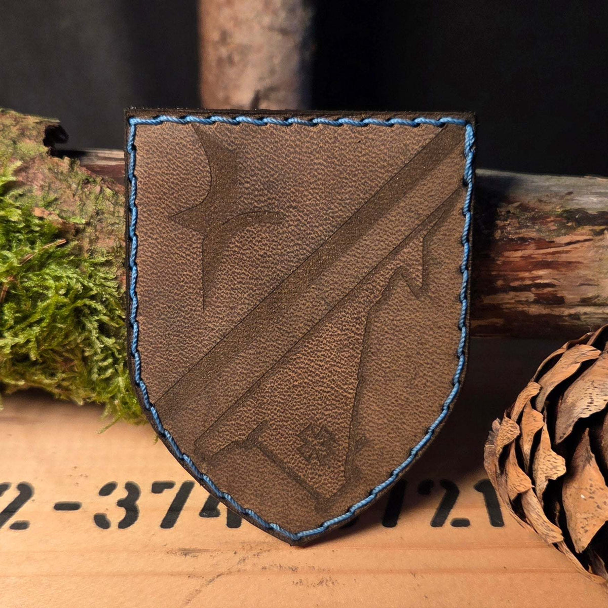 Individueller Leder Patch aus braunem Büffelleder mit dezentem, handvernähtem blauen Rand und graviertem Schild-Design