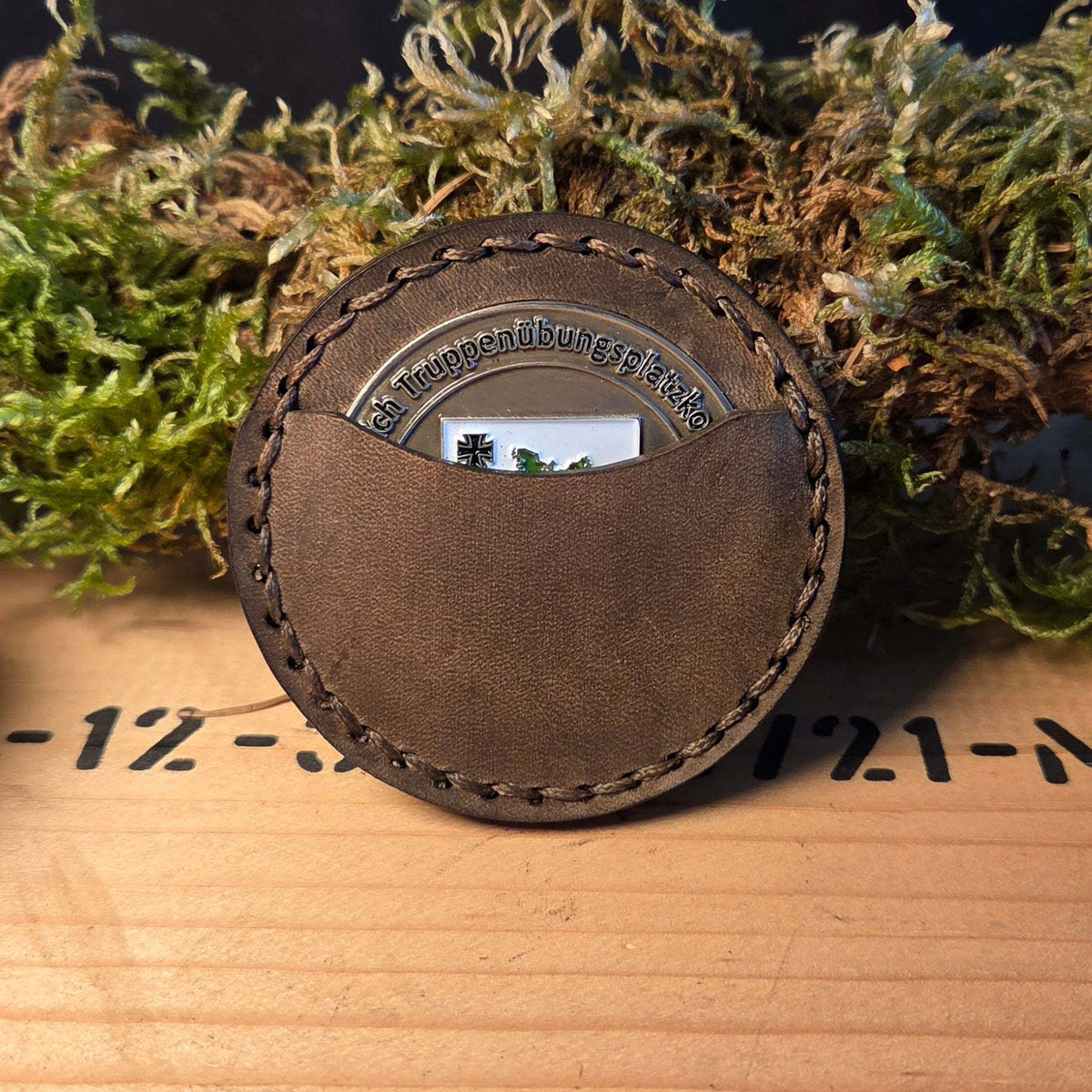 Runde Leder Coinhülle in braun mit handvernähten Kanten und einem sichtbaren silbernen Coin als Einsatz