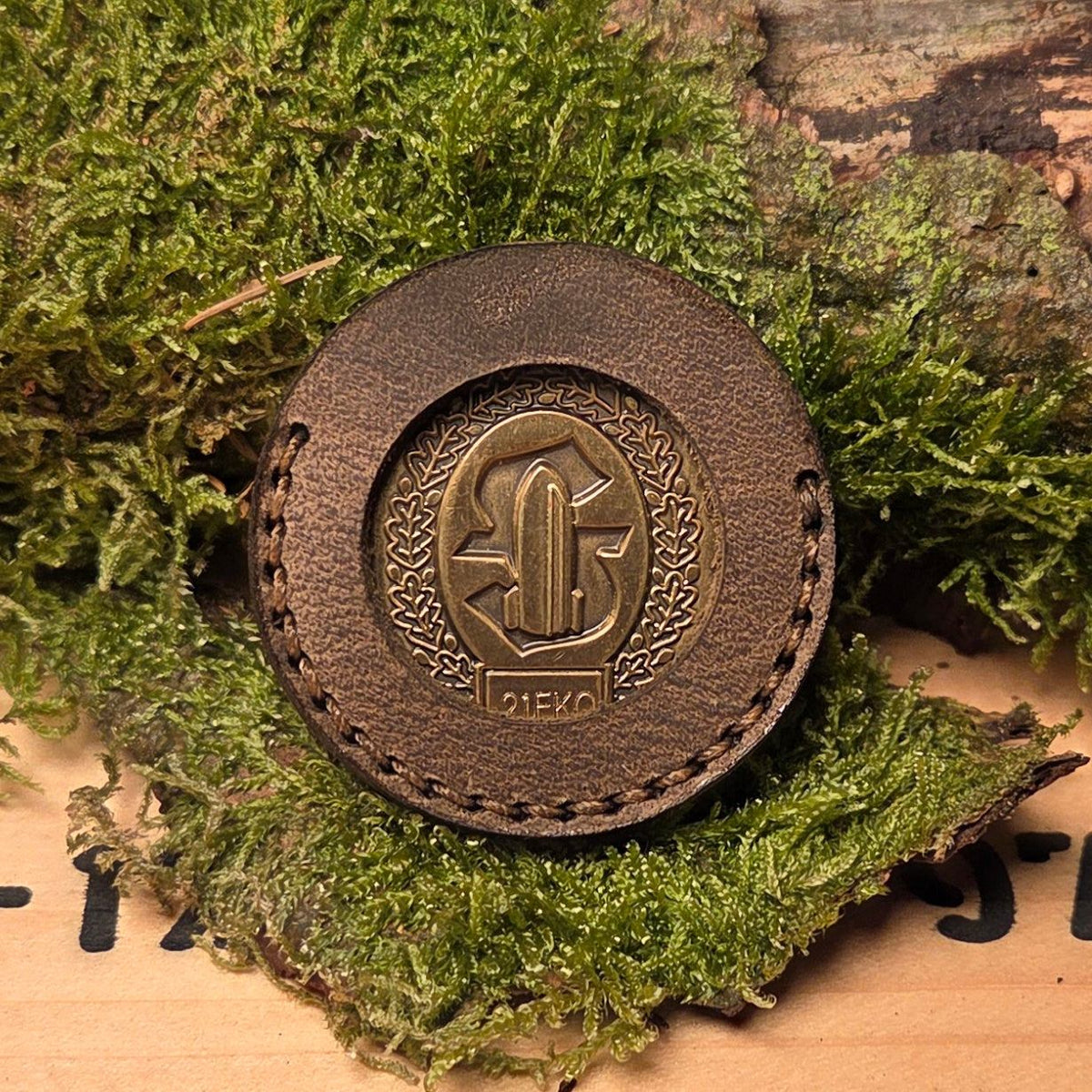 Runde Leder Coinhülle in braun mit handvernähter Kante und mittig eingelassener goldfarbener Medaille mit Wappenmotiv