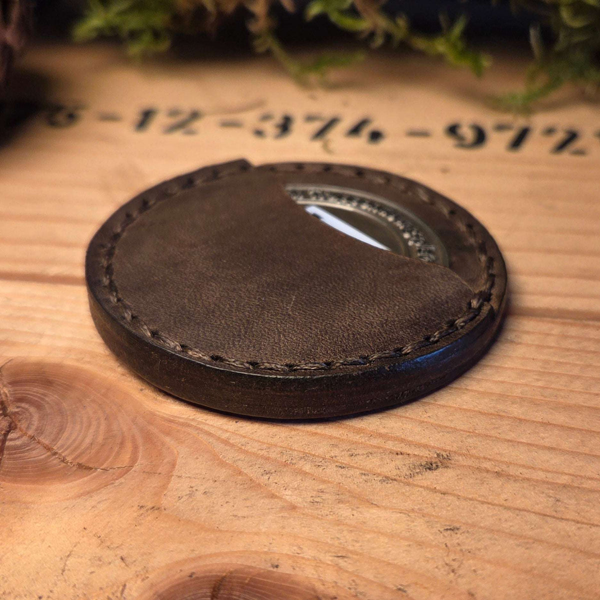Runde Leder Coinhülle in dunkelbraun mit handvernähten Kanten und sichtbarem Münzfenster aus Vollnarbenleder