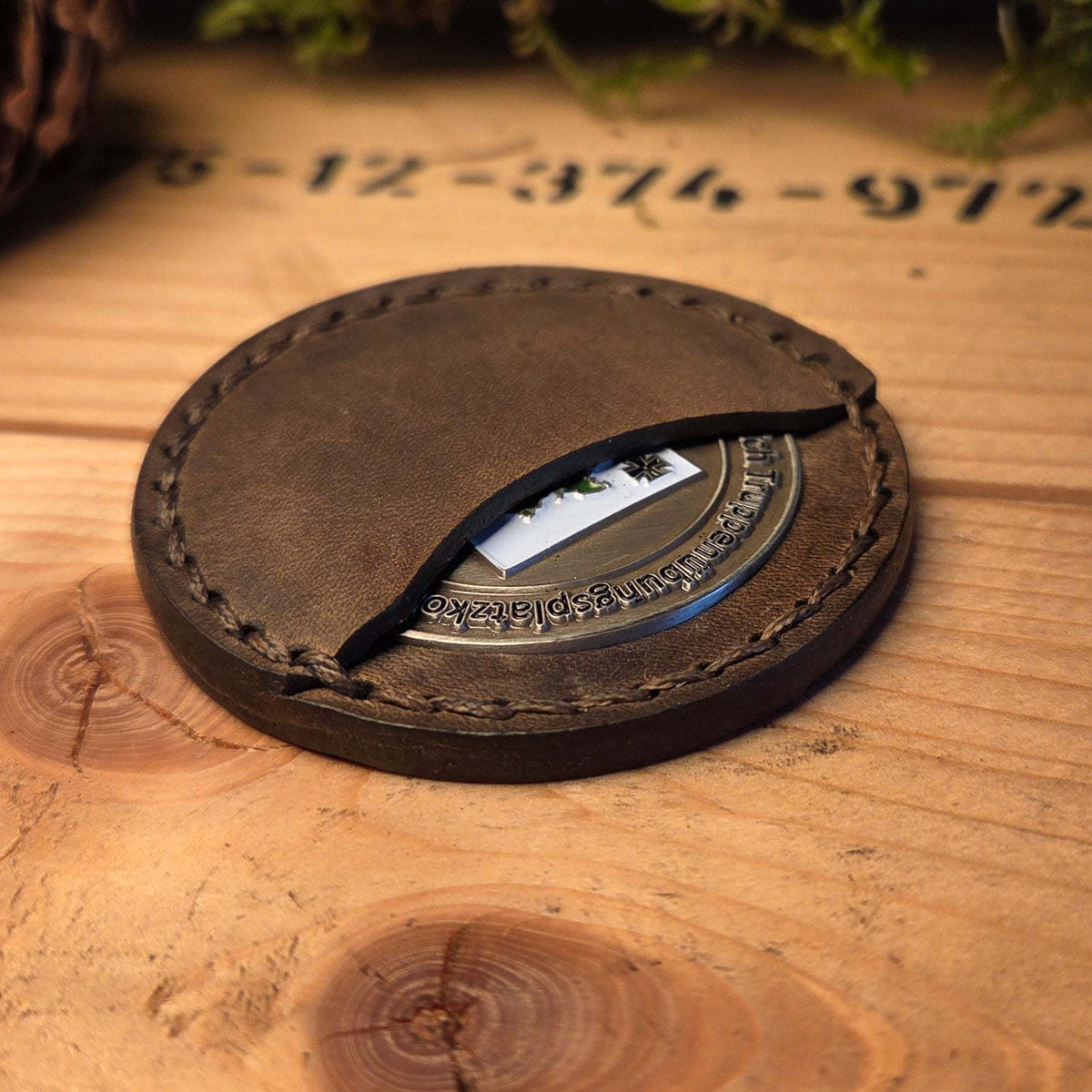 Runde Leder Coinhülle in braun mit sichtbarer Münze und handvernähtem Detail für sicheren Schutz