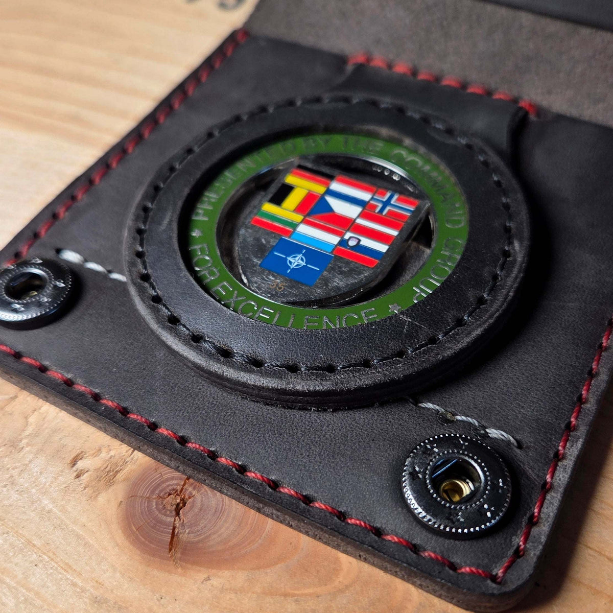 Leder-Dienstausweisetui aus schwarzem Echtleder mit roten und weißen Nähten, sichtbarem Markenhalter mit NATO-Flaggen-Motiv und Druckknopfverschluss