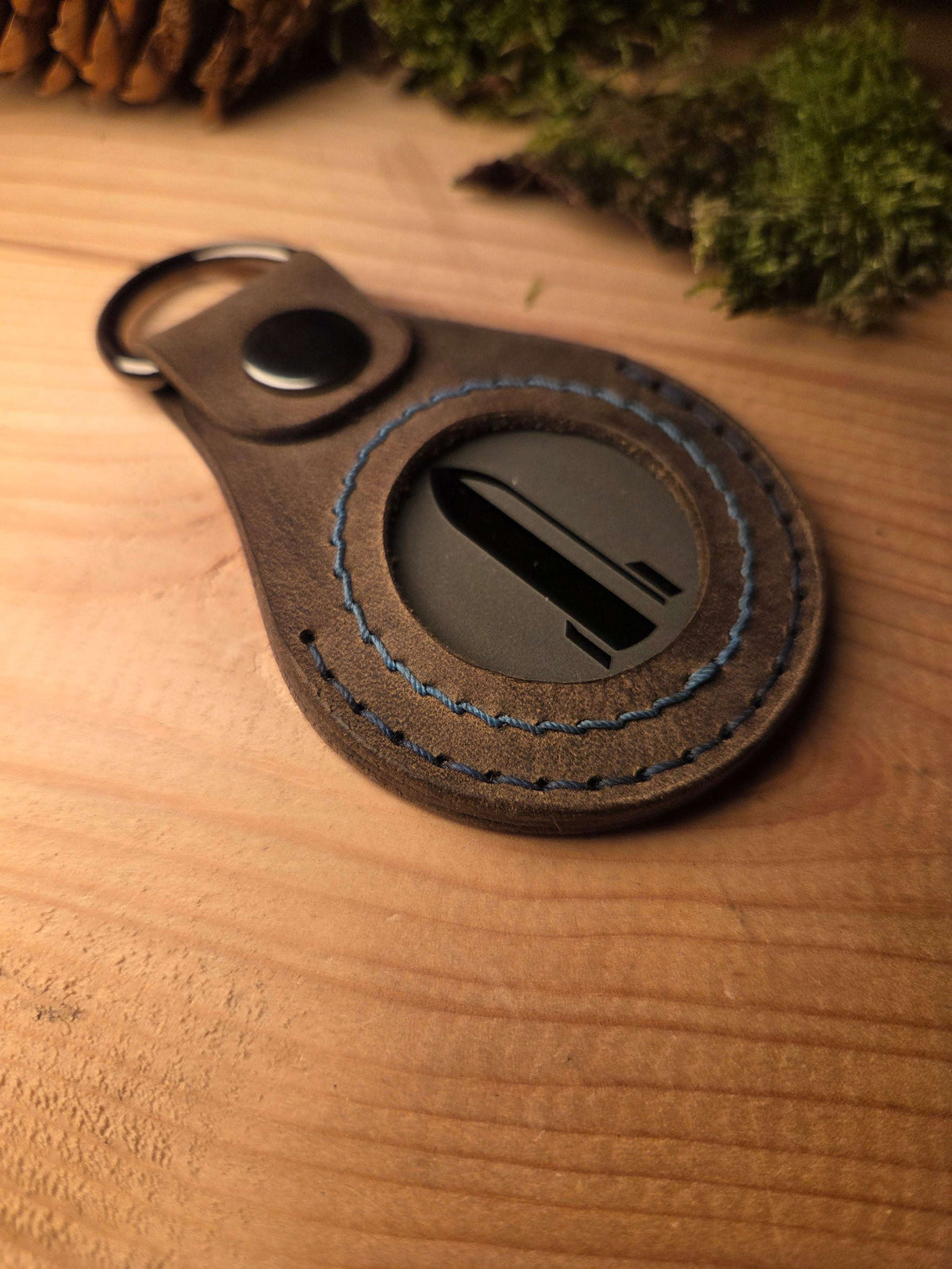 Lederanhänger für Challenge Coin aus braunem Echtleder mit blauem Zierstich und schwarzem D-Ring zur Befestigung