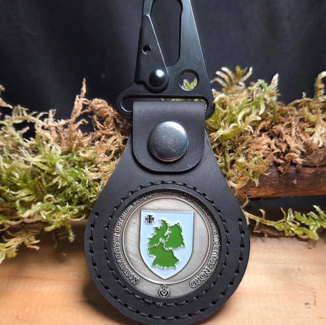 Schwarzer Lederanhänger für Challenge Coin mit sichtbarem Coin in grün-weißem Deutschland-Design und robustem Karabiner