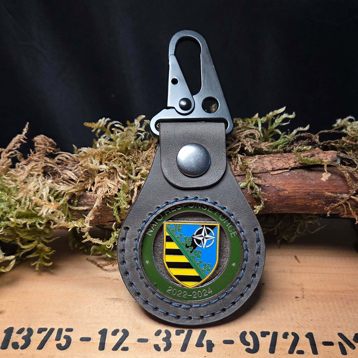 Lederanhänger für Challenge Coin in braunem Echtleder mit sichtbarem Militär-Emblem und schwarzem Karabinerhaken
