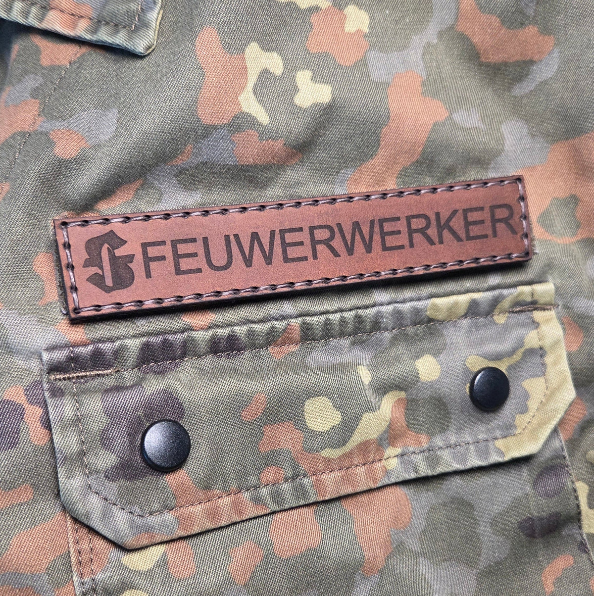 Namensband aus Leder in Braun mit handvernähter Naht und schwarzer Schrift Feuwerker auf Tarnjacke