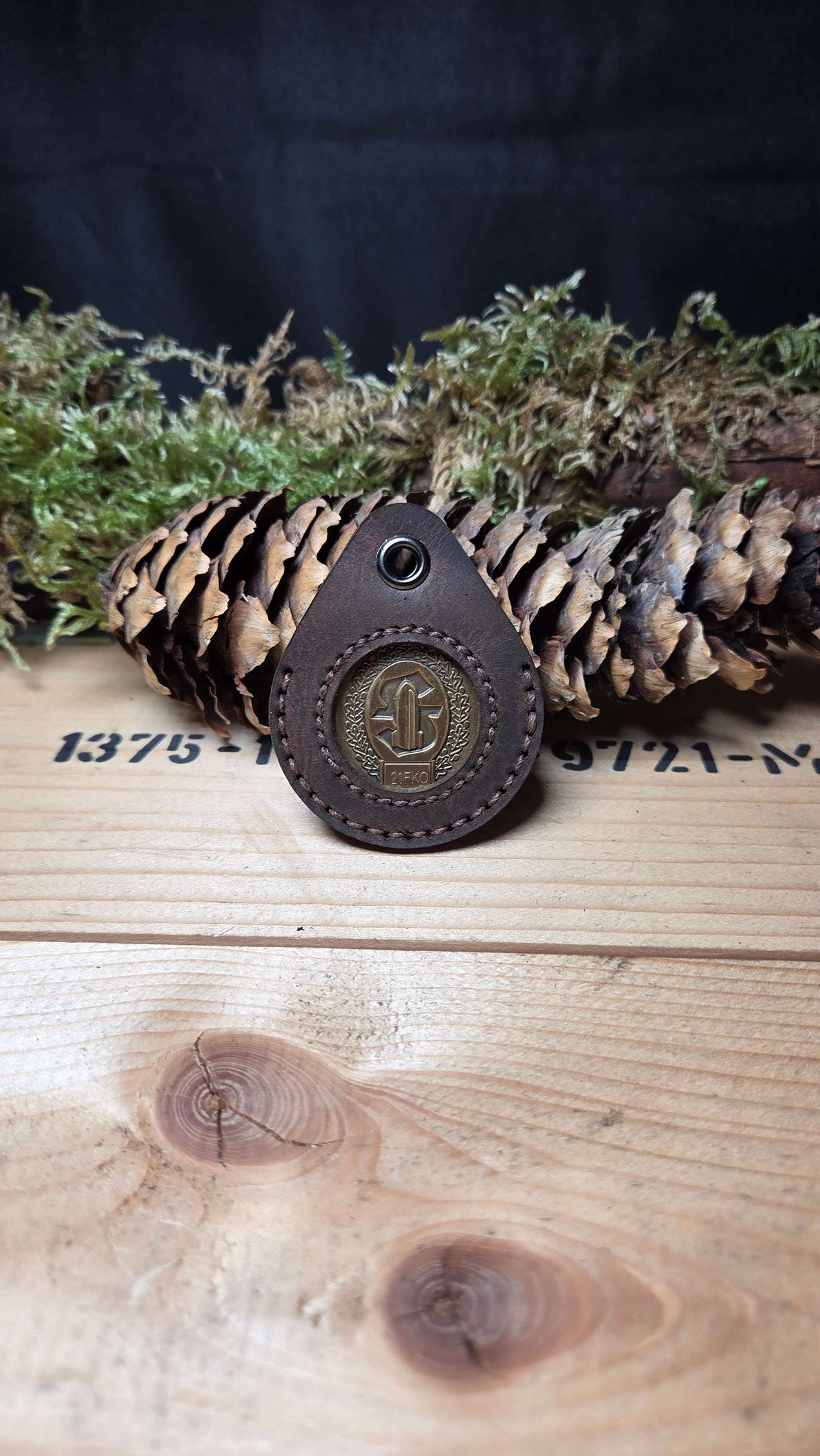 Schlüsselanhänger aus Leder in braun mit geprägtem runden Coin in der Mitte und dekorativer Naht am Rand