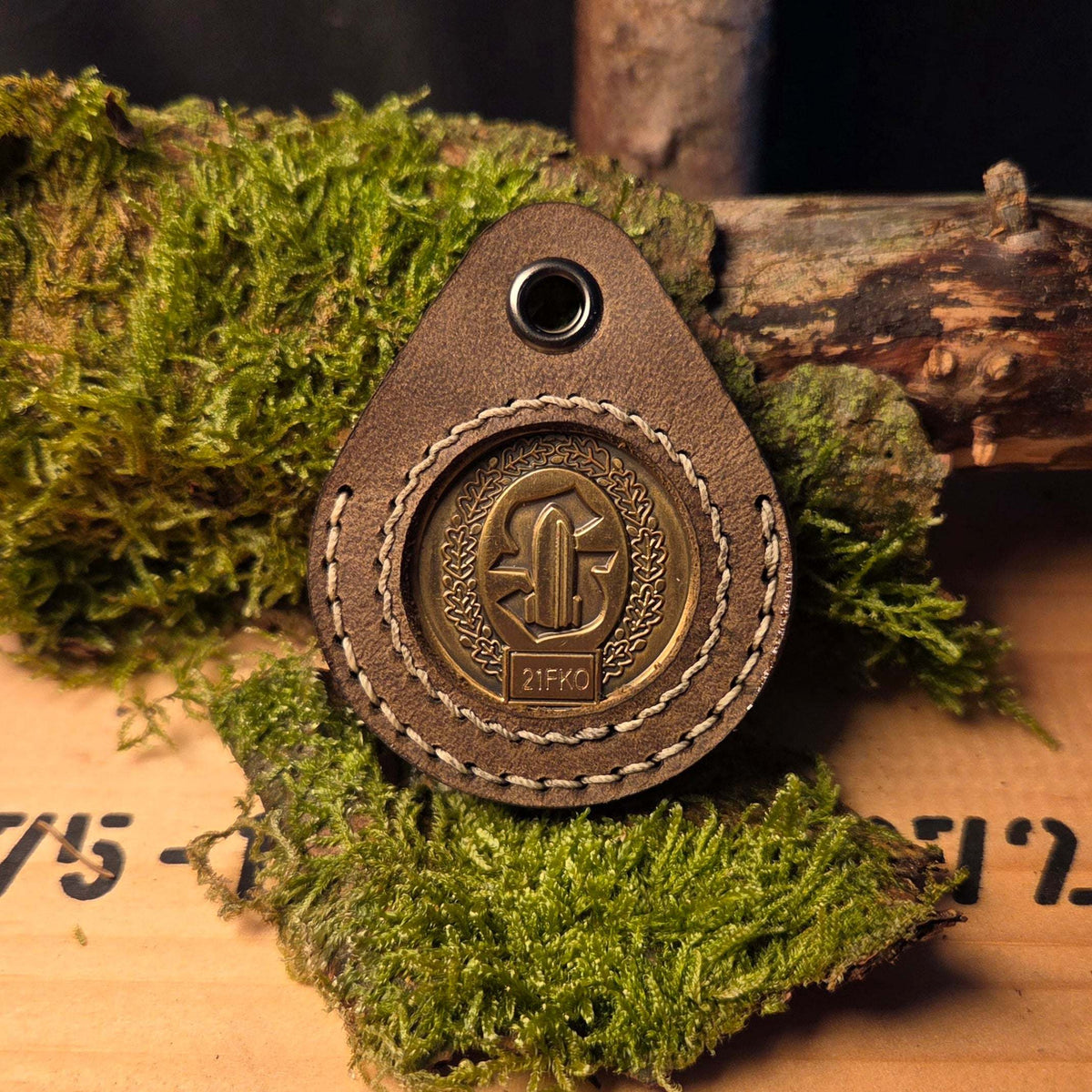 Schlüsselanhänger aus Leder in brauner Farbe mit handgenähter Naht und metallischer Challenge Coin Halterung in der Mitte
