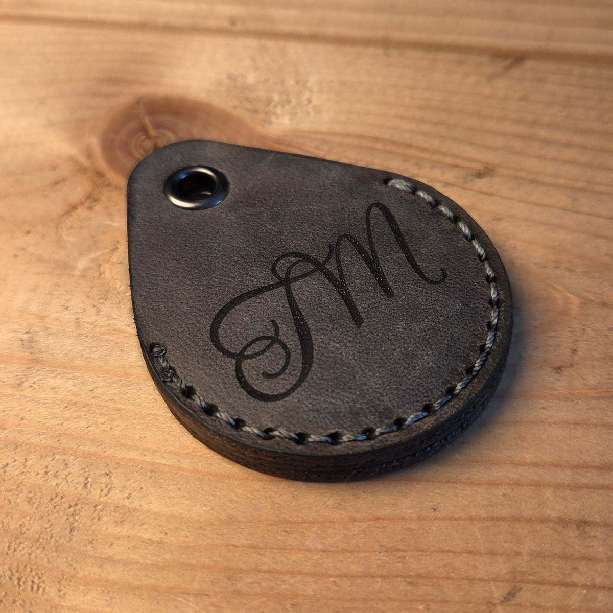 Schlüsselanhänger aus Leder in Tropfenform, dunkelgraues Büffelleder mit grauer Naht und Gravur der Initialen "M"