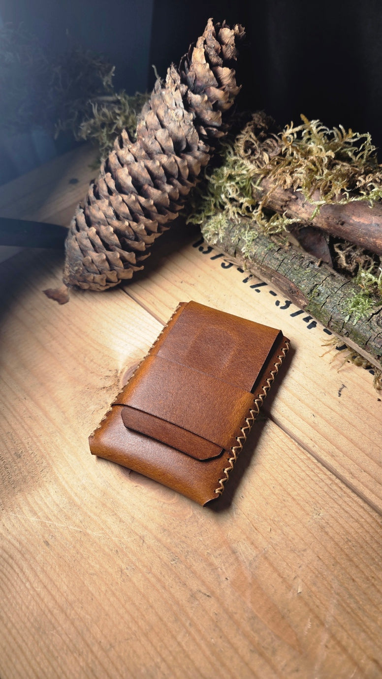 Slim Wallet aus Leder in braun mit handgenähten Nähten und minimalistischem Design auf Holzuntergrund