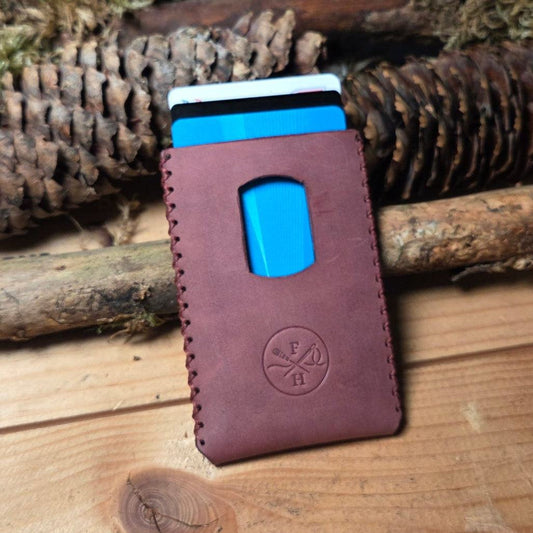 Slim Wallet aus Leder in dunklem Braun mit sichtbarer Handnaht, geprägtem Logo und praktischem Kartenausgabefenster