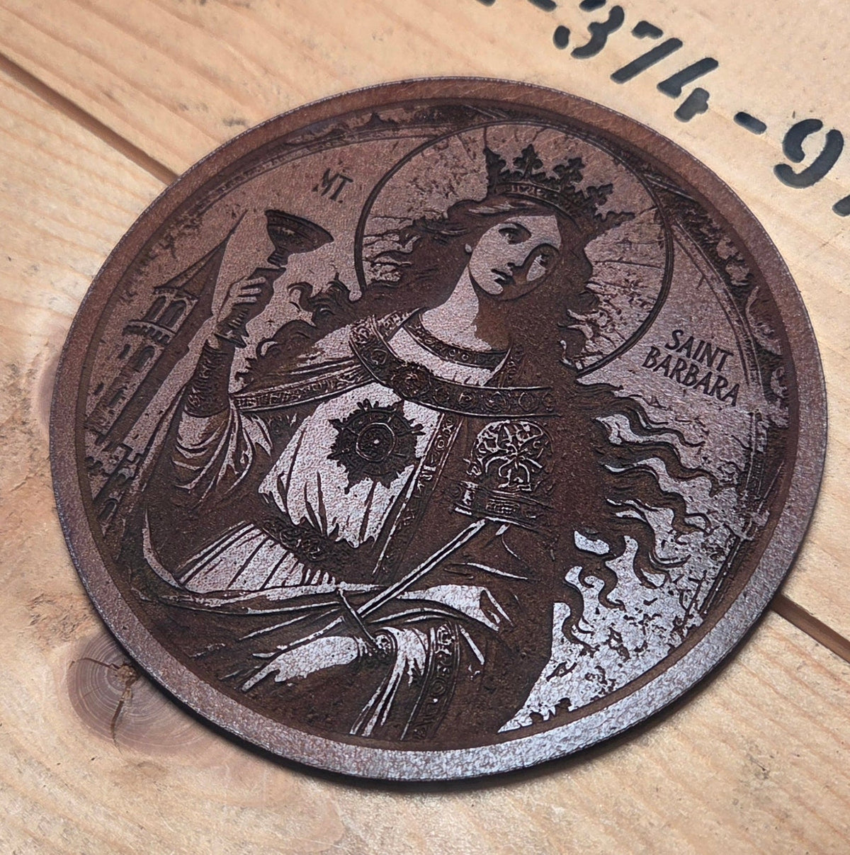 Runder Untersetzer aus Leder in Dunkelbraun mit detailreicher Lasergravur der Heiligen Barbara und filigranem Design